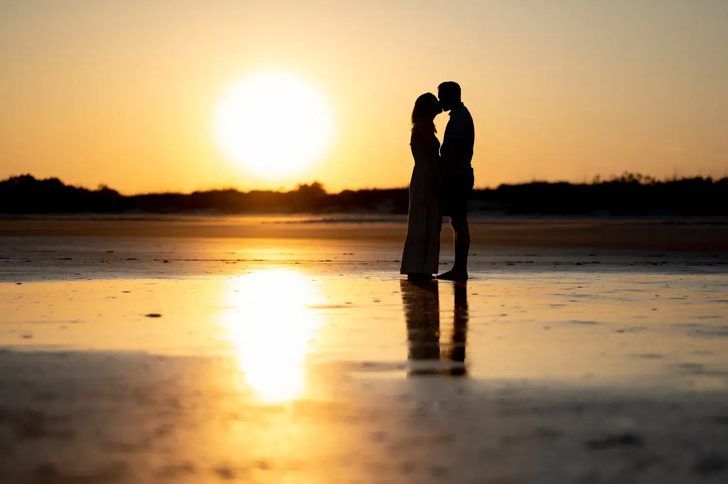 A couple silhouetted together on the beach at sunset